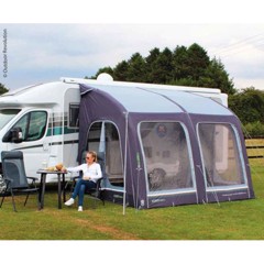 Telt med vinduer ved siden av en campervan. Person sitter utenfor, nyter fritiden på en gressplen.